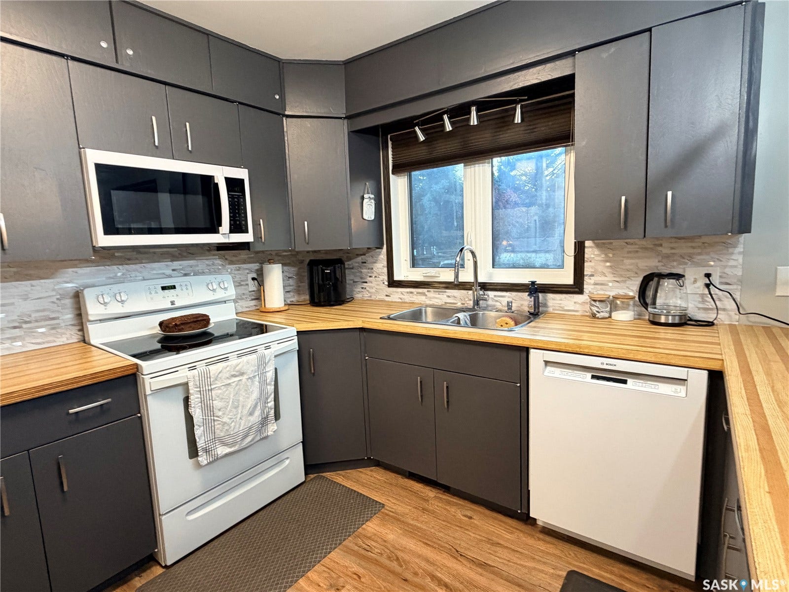 Kitchen with gray cabinetry, wood-finish countertops, and a tile backsplash