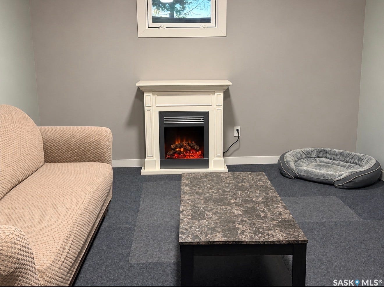 White electric fireplace with mantel, gray wall paint, and modular carpet flooring