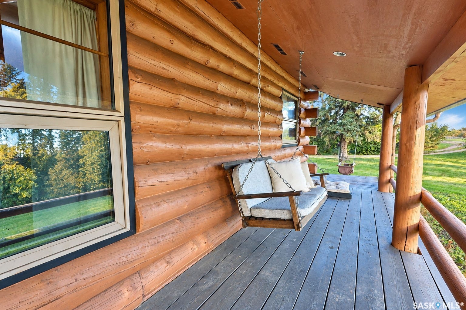 Expansive covered porch with a log cabin exterior, wood-finish flooring, and natural wood railings