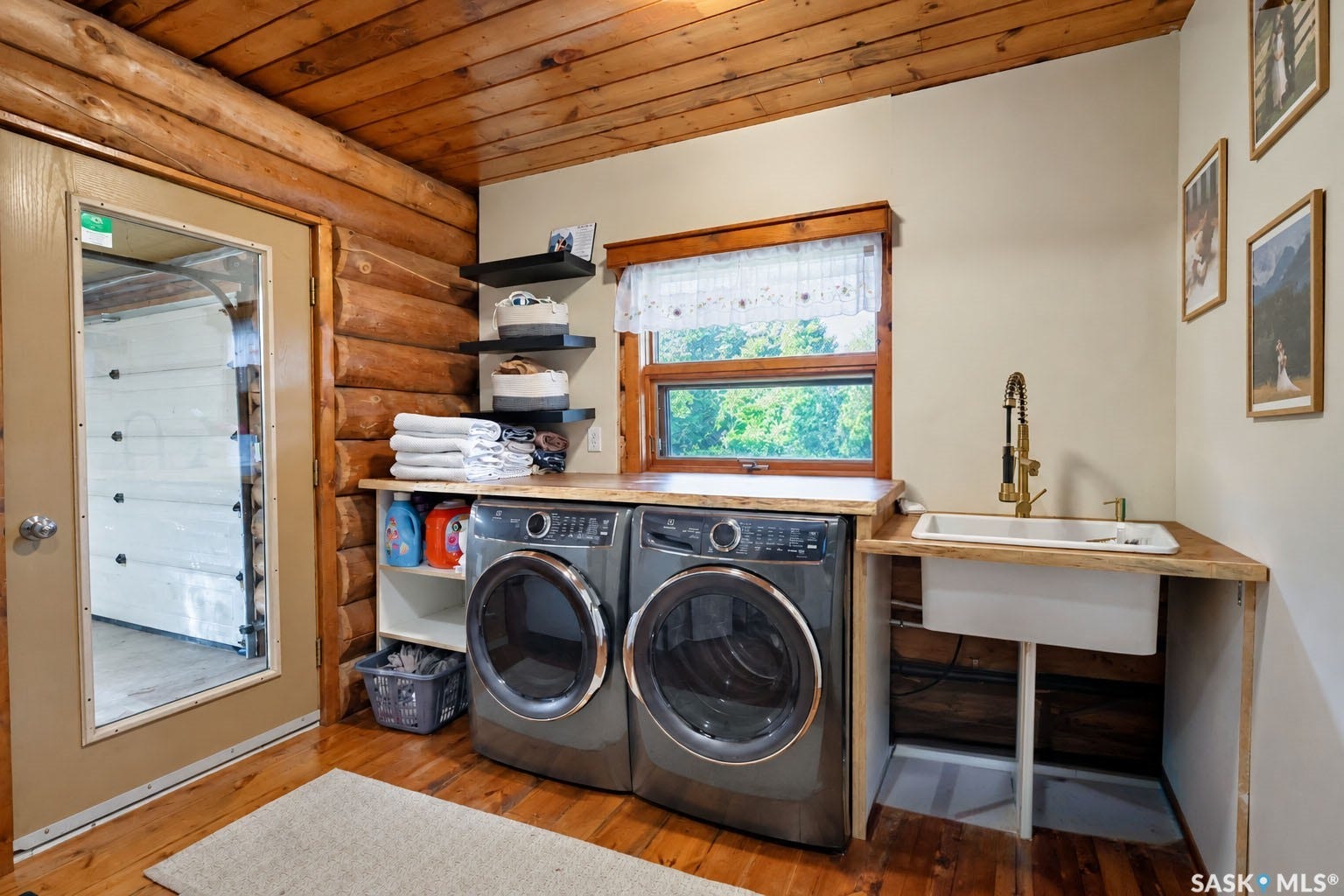 Wood-paneled ceilings, log wall construction, wood-finish flooring, built-in shelving, and a utility sink with a brass-finish faucet