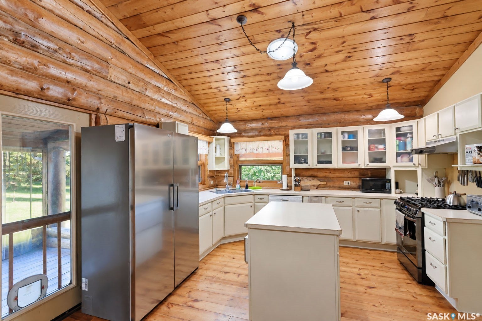 Vaulted wood-paneled ceiling, wood-finish flooring, white cabinetry, stainless steel refrigerator, and central island