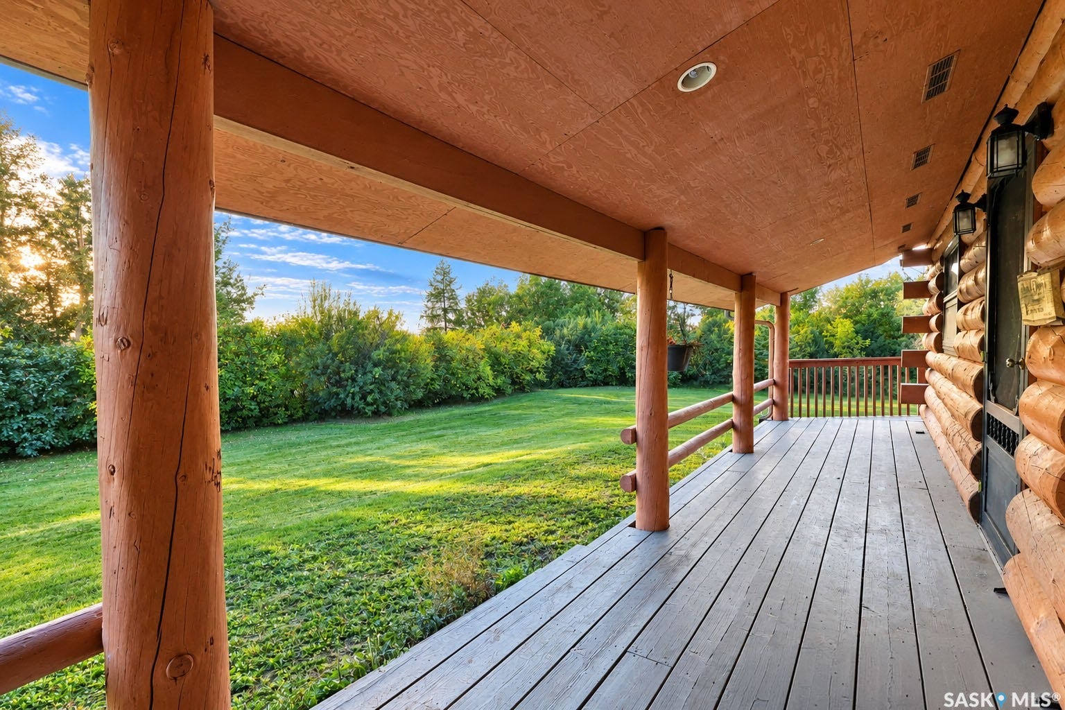 Covered porch with wood-finish decking, log supports, and recessed lighting