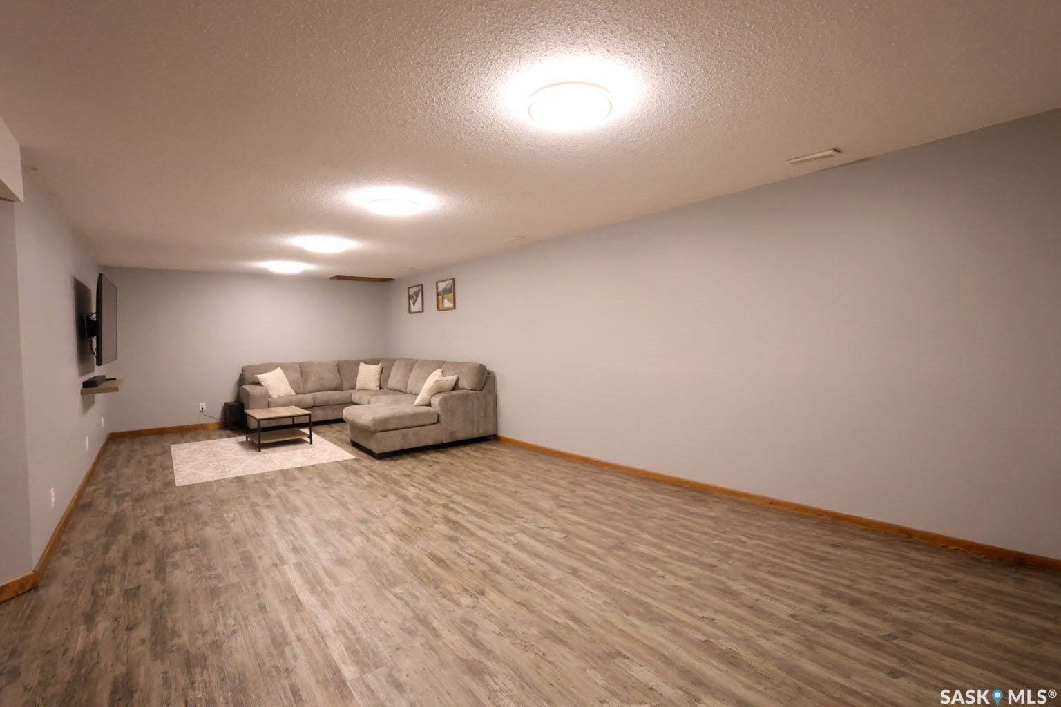 Spacious room with wood-finish flooring, light gray walls, and recessed lighting