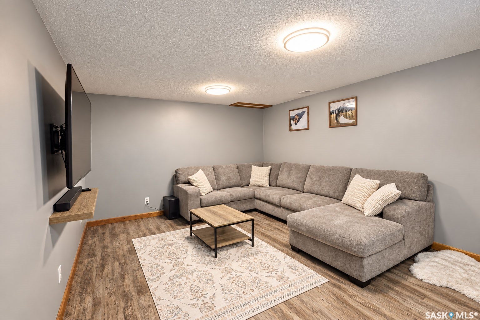 Recessed lighting illuminates the space, featuring wood-finish flooring and a floating wall shelf