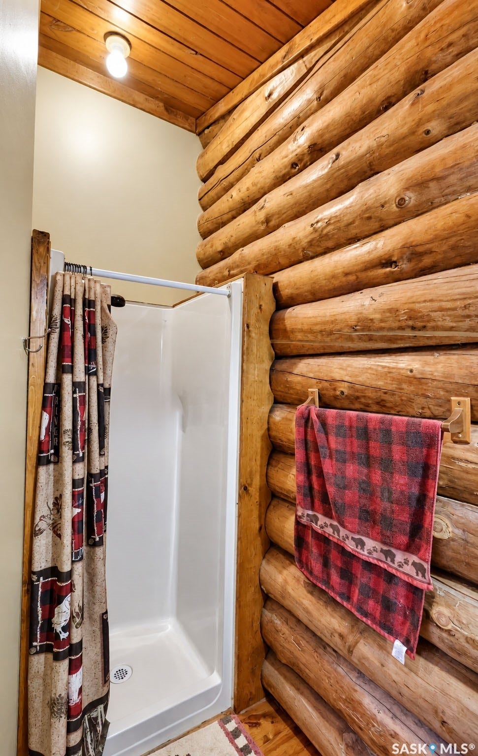 Log wall construction, wood-paneled ceiling, and a white shower stall
