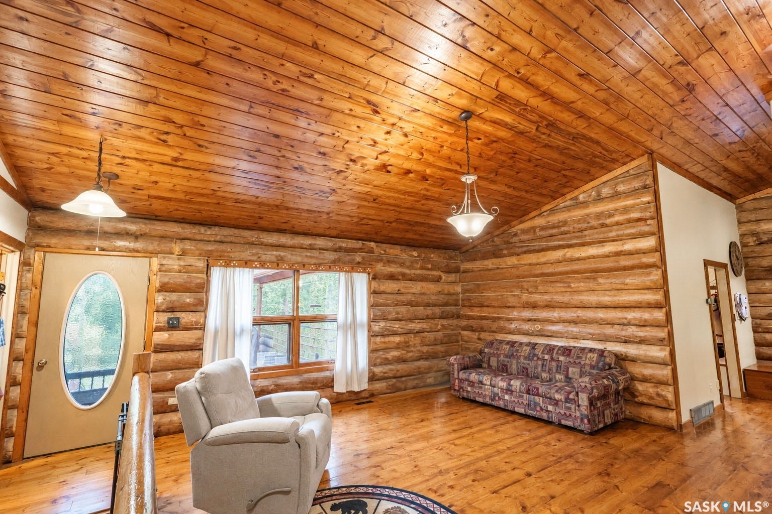 Wood-paneled ceilings, wood-finish flooring, exposed log walls, and prominent windows with a wood frame