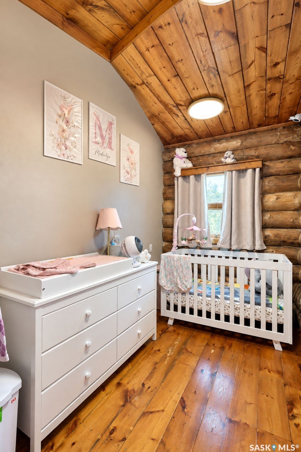 Vaulted wood-paneled ceiling, wood-plank flooring, and exposed log wall
