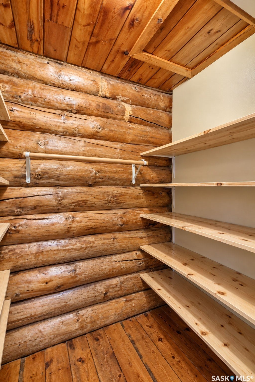 Log walls, wood-finish flooring, wood-paneled ceiling, built-in shelving, and a hanging rod