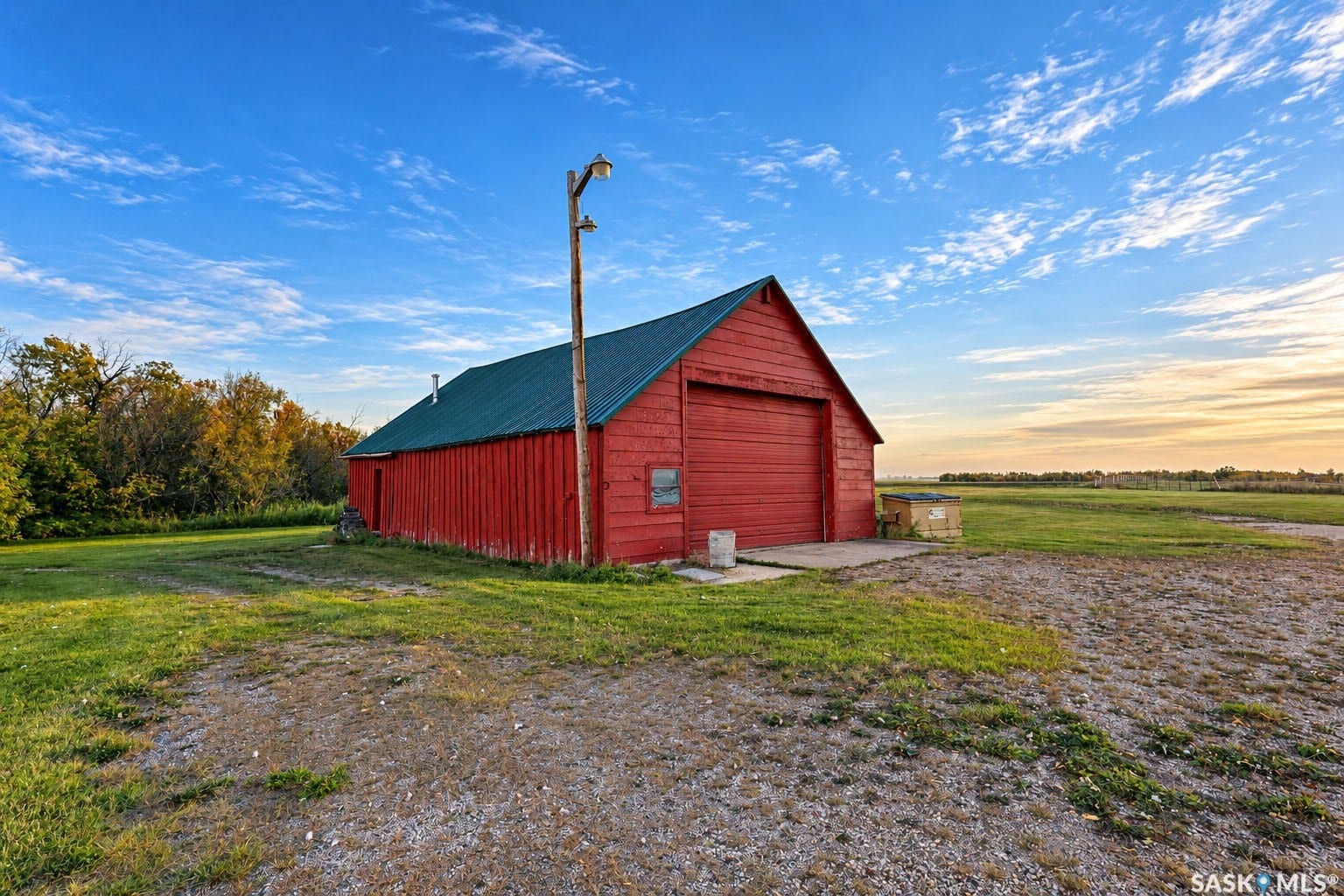 Red-sided barn structure with a green metal roof and a large garage door
