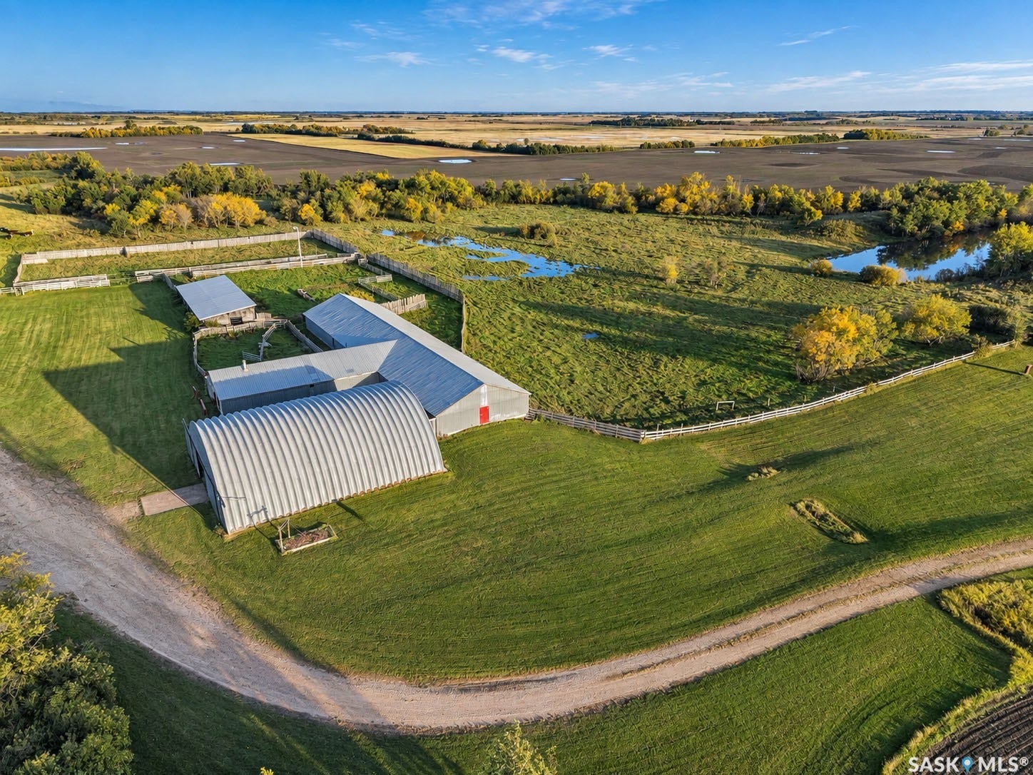 Expansive property featuring multiple outbuildings, fenced enclosures, and a large quonset hut