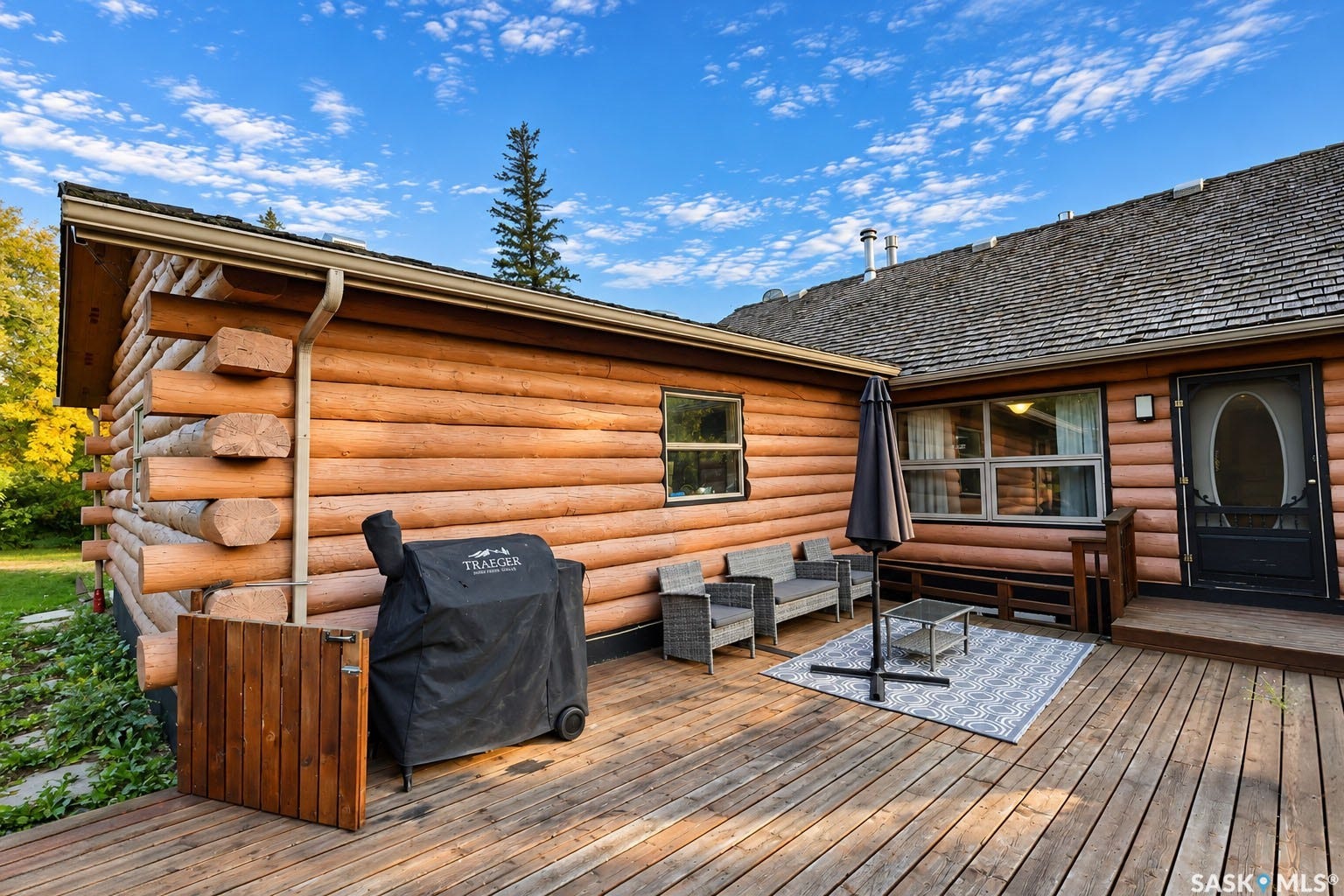 Expansive wood deck with log-style exterior, multiple windows, and a shingled roof