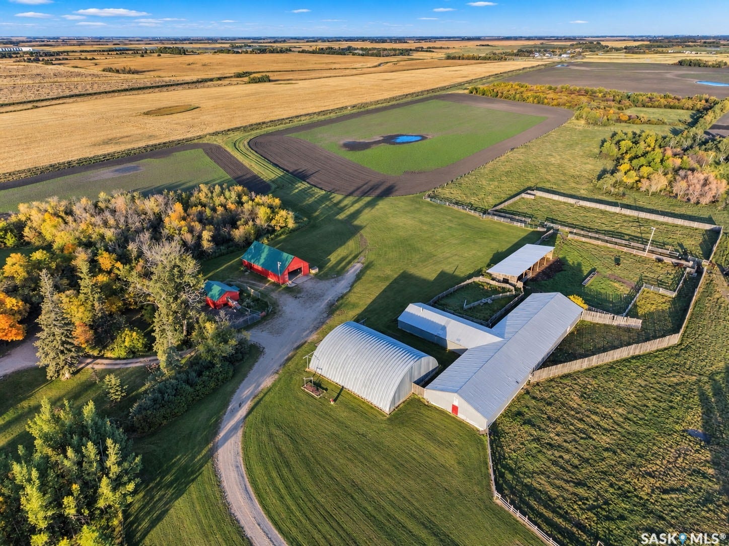 Expansive property featuring multiple outbuildings, fenced enclosures, and a large cultivated field