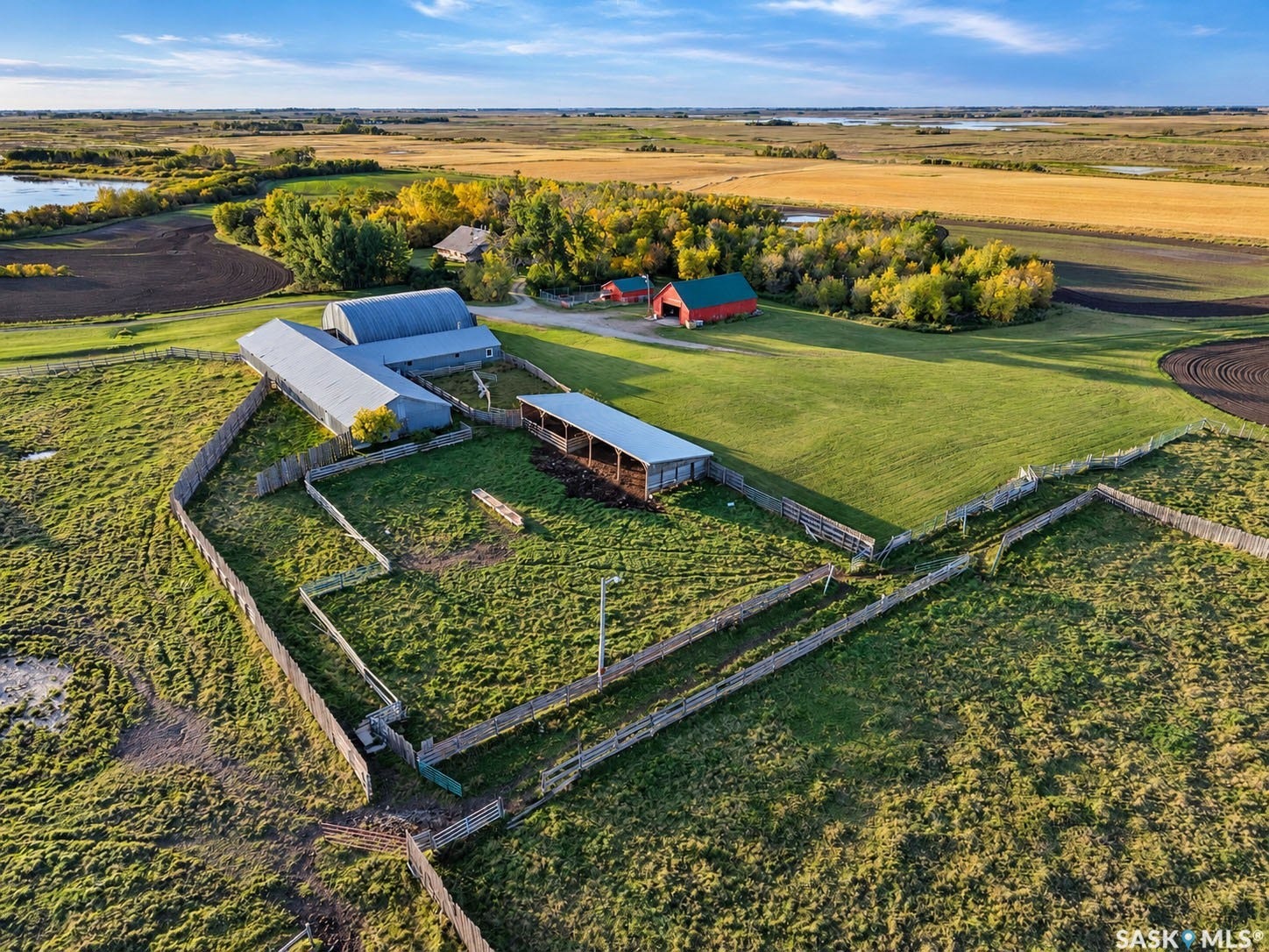 Expansive rural acreage featuring multiple outbuildings, fenced enclosures, and surrounding agricultural fields