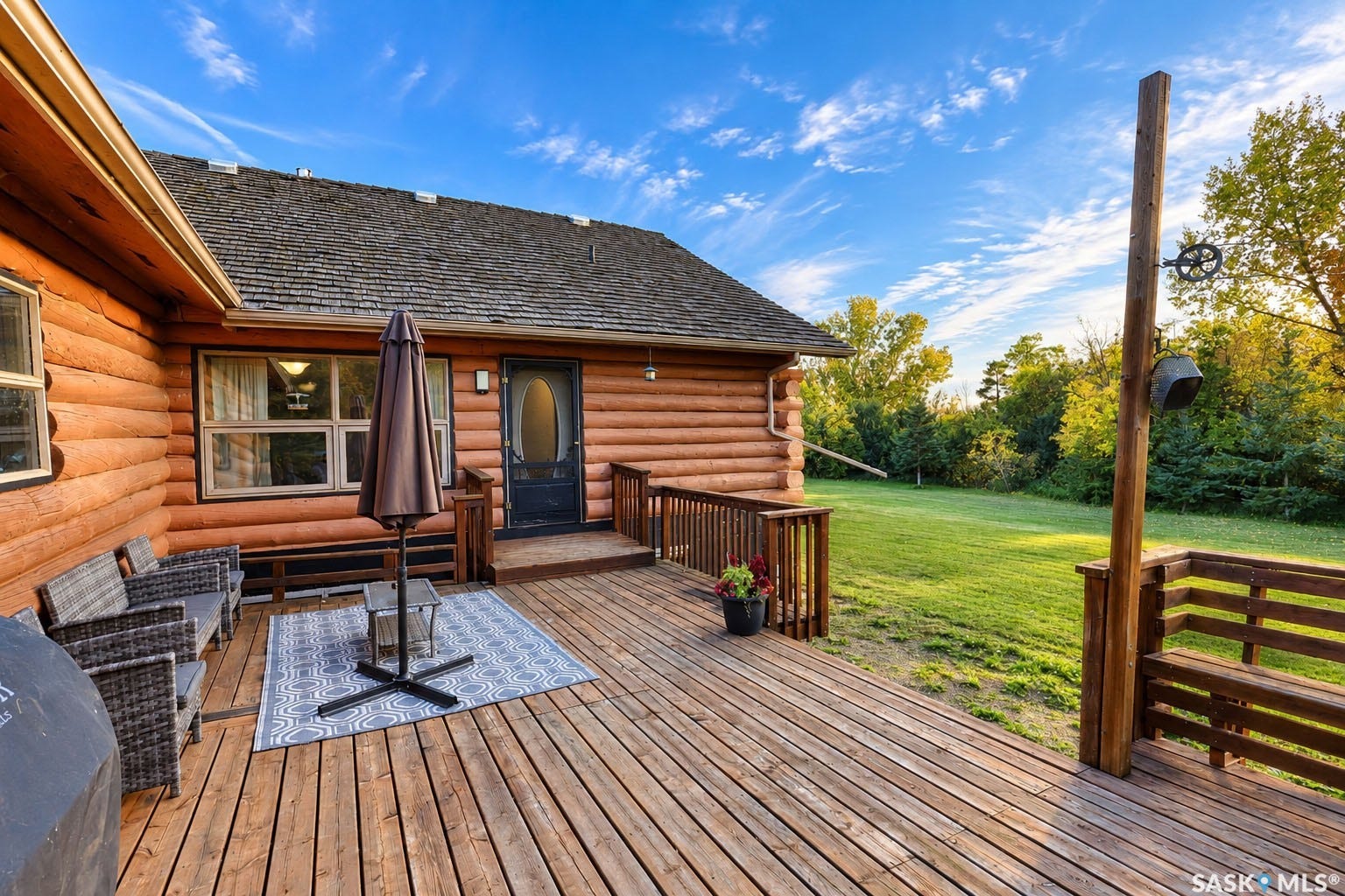 Spacious wood-plank deck with a log cabin exterior, shingle roof, and a built-in wooden railing