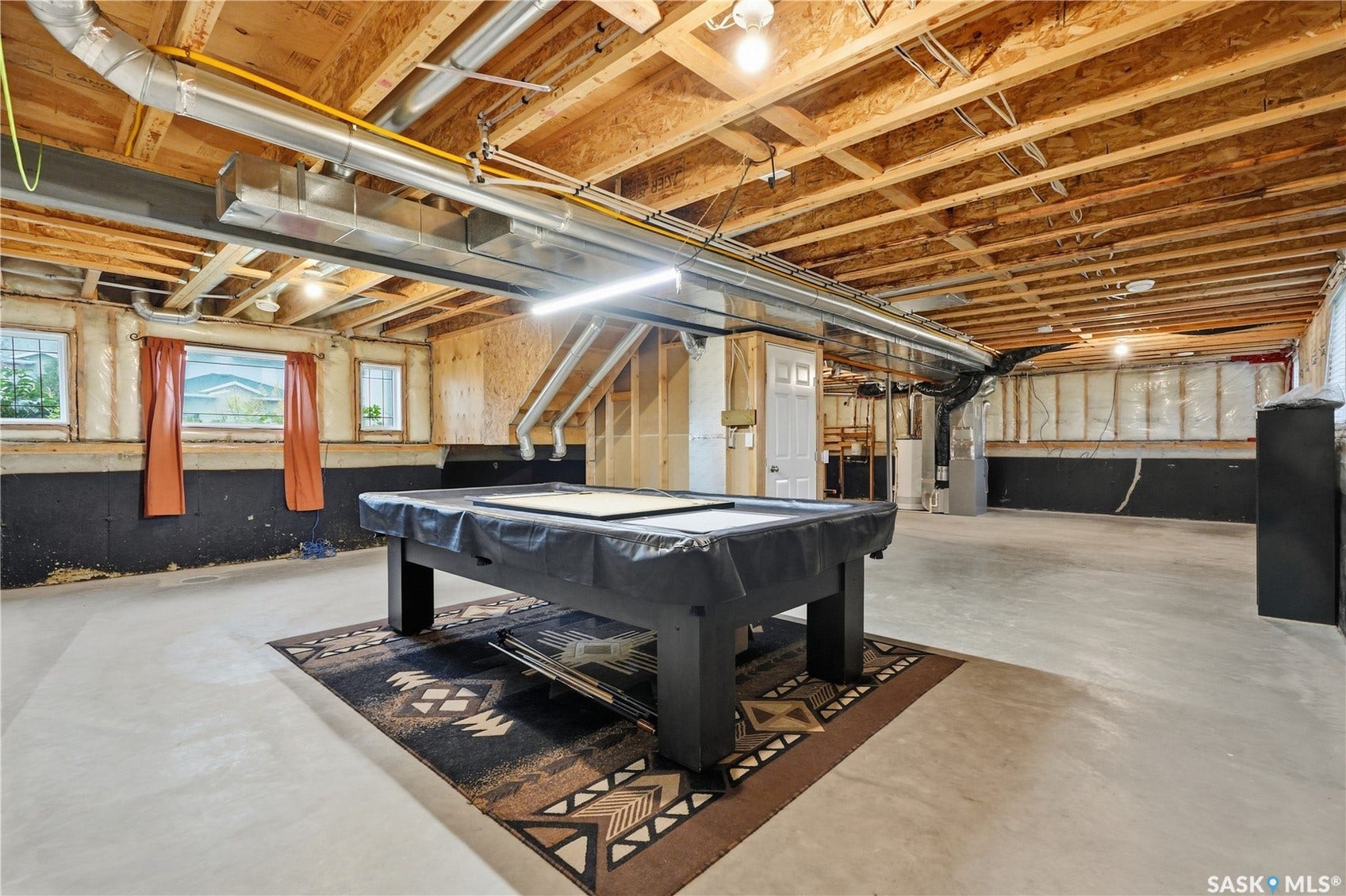 Unfinished basement with exposed ceiling joists and concrete flooring