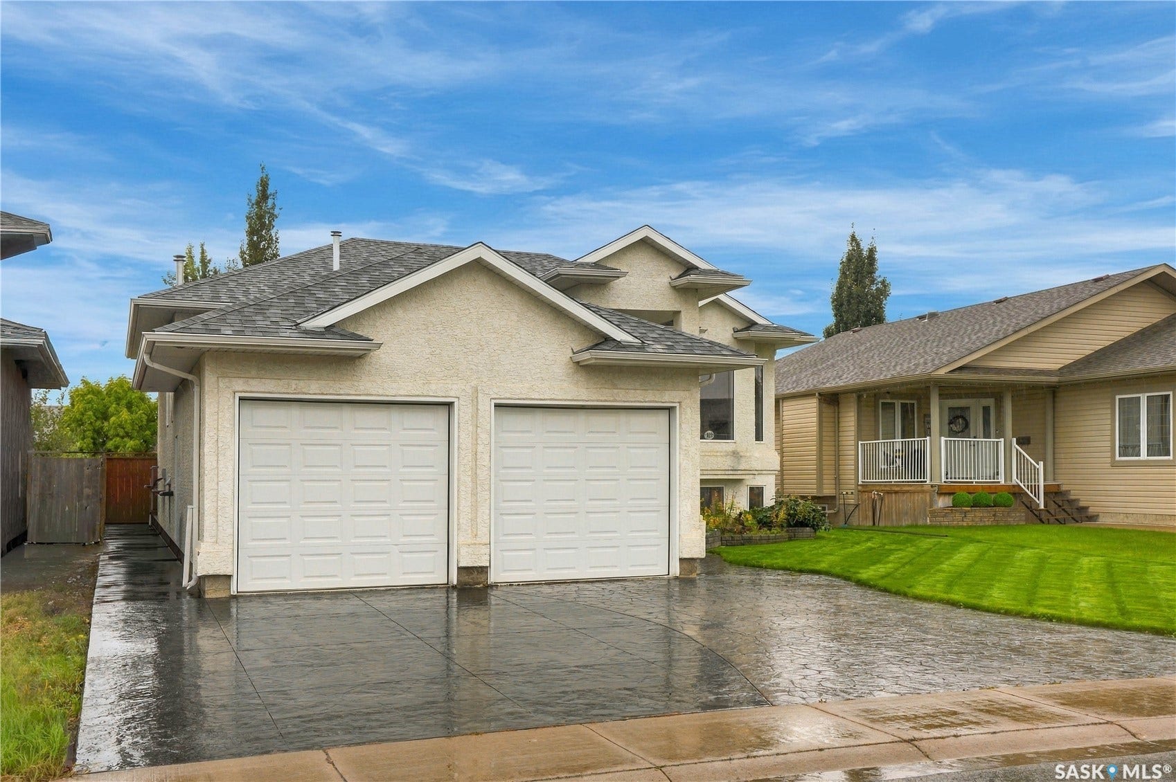 Stucco exterior with a dual garage featuring white doors, a patterned concrete driveway, and asphalt shingle roofing