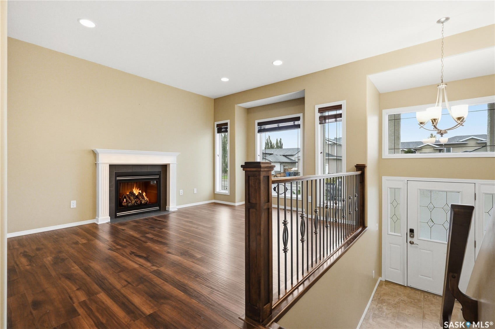 Spacious living area featuring wood-finish flooring, a fireplace with a white mantel, and recessed lighting