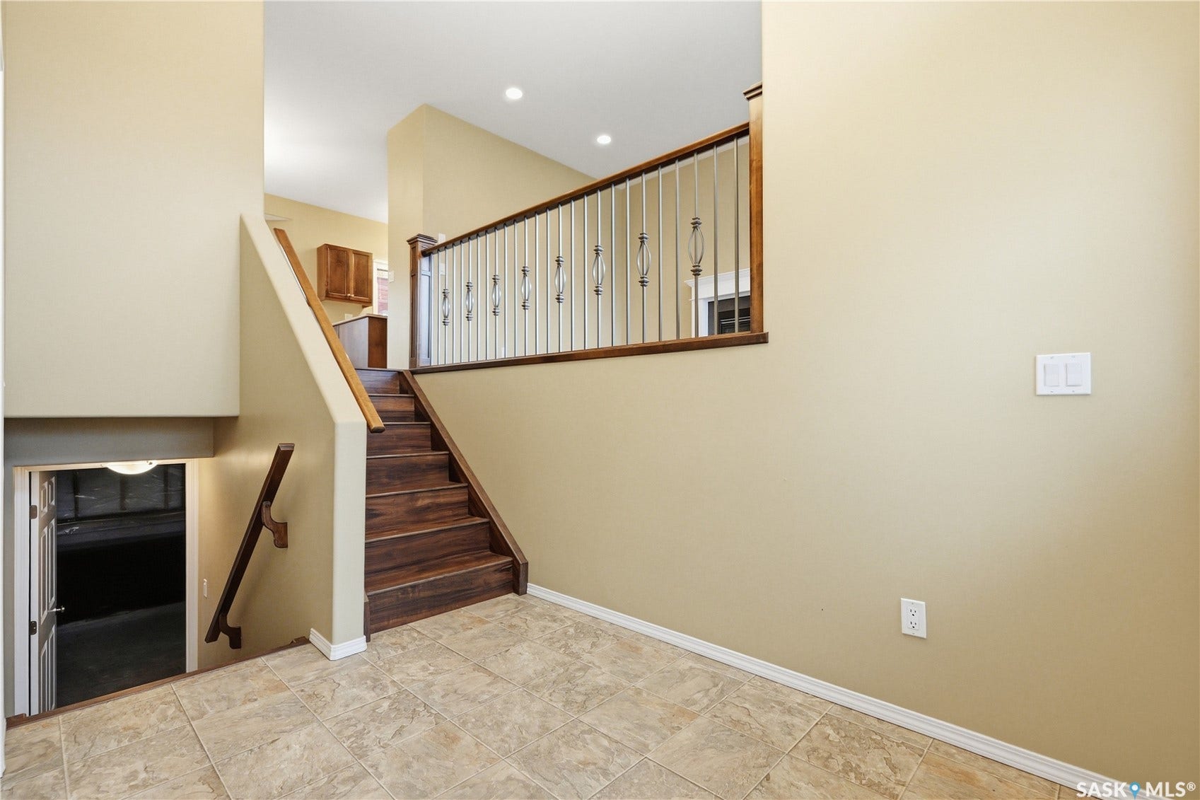 Two-tone wall paint, wood-finish flooring on stairs, tile flooring, built-in recessed lighting, and wood railing with metal balusters