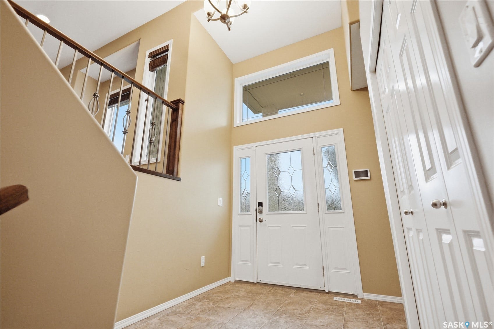 Entryway featuring a decorative glass front door with sidelights, a transom window, and tile flooring