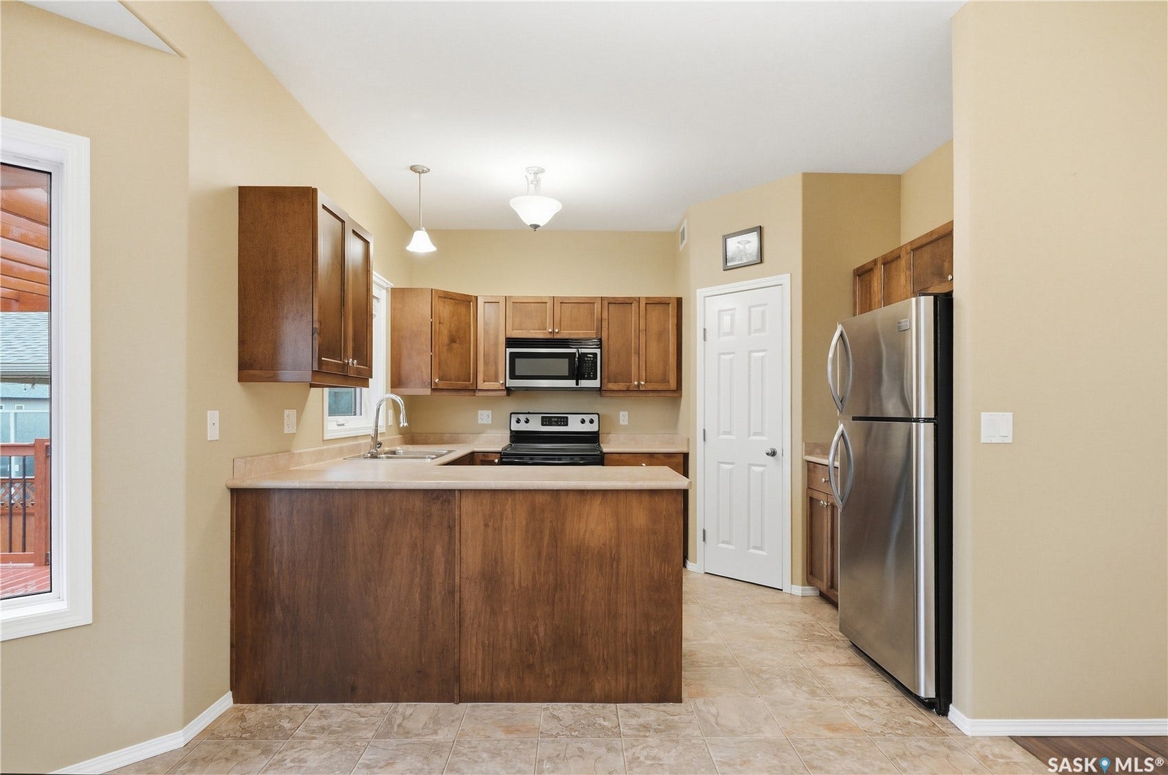 U-shaped kitchen with wood cabinetry, stainless steel appliances, and a tiled floor