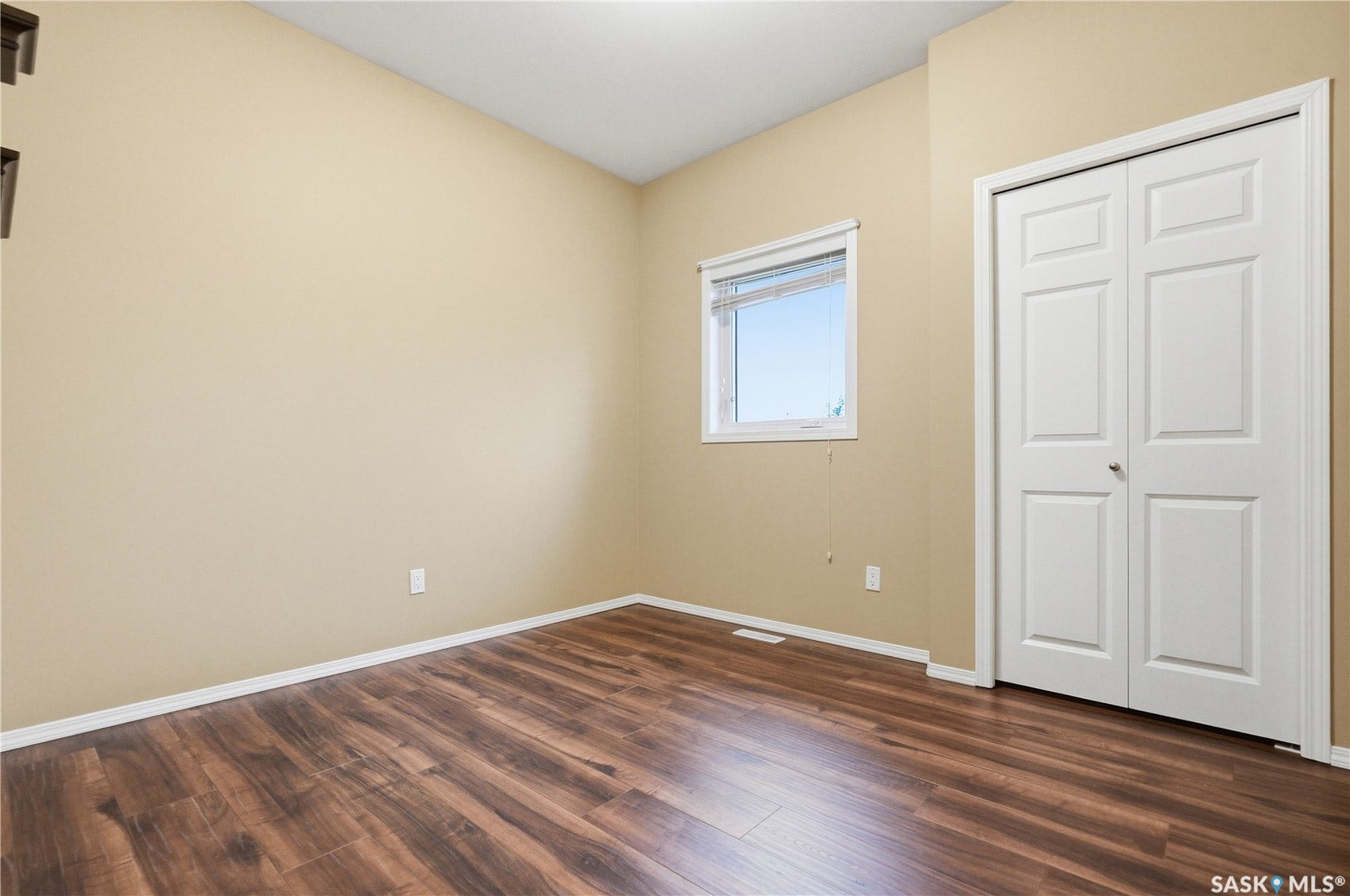 Wood-finish flooring, neutral wall tones, white trim, and a white bi-fold door