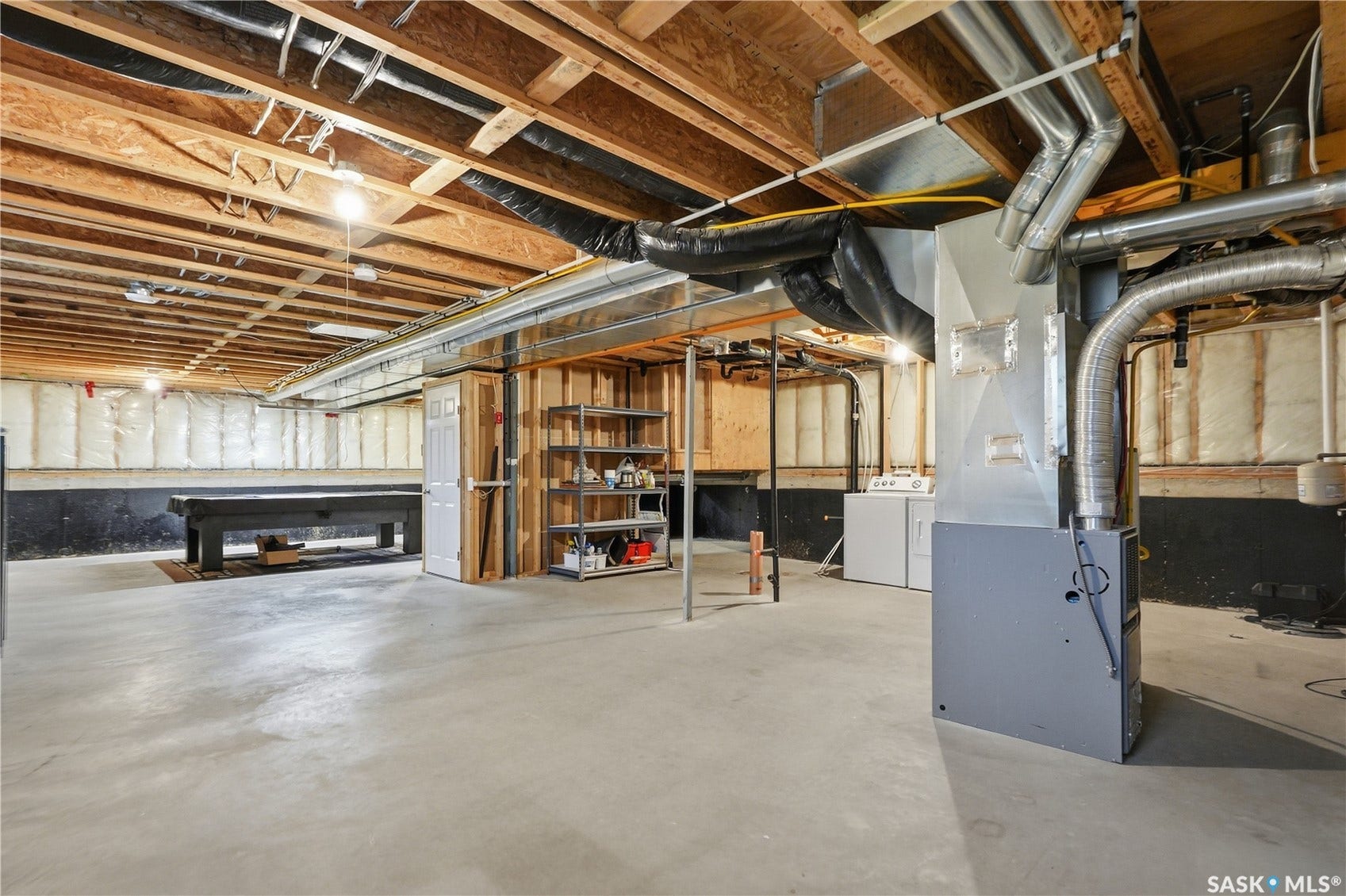 Unfinished basement featuring exposed wood joists, concrete flooring, and existing utility infrastructure