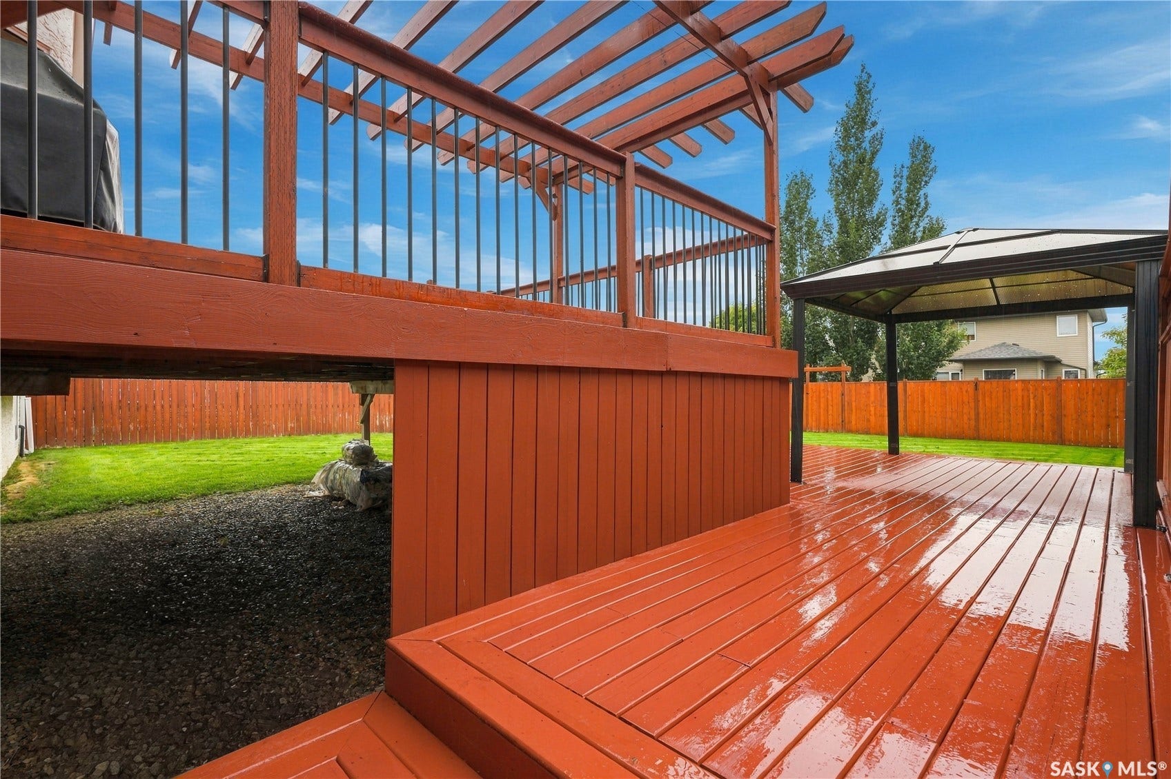 Multi-level wood deck featuring a pergola, black metal railings, and a lower-level covered patio area