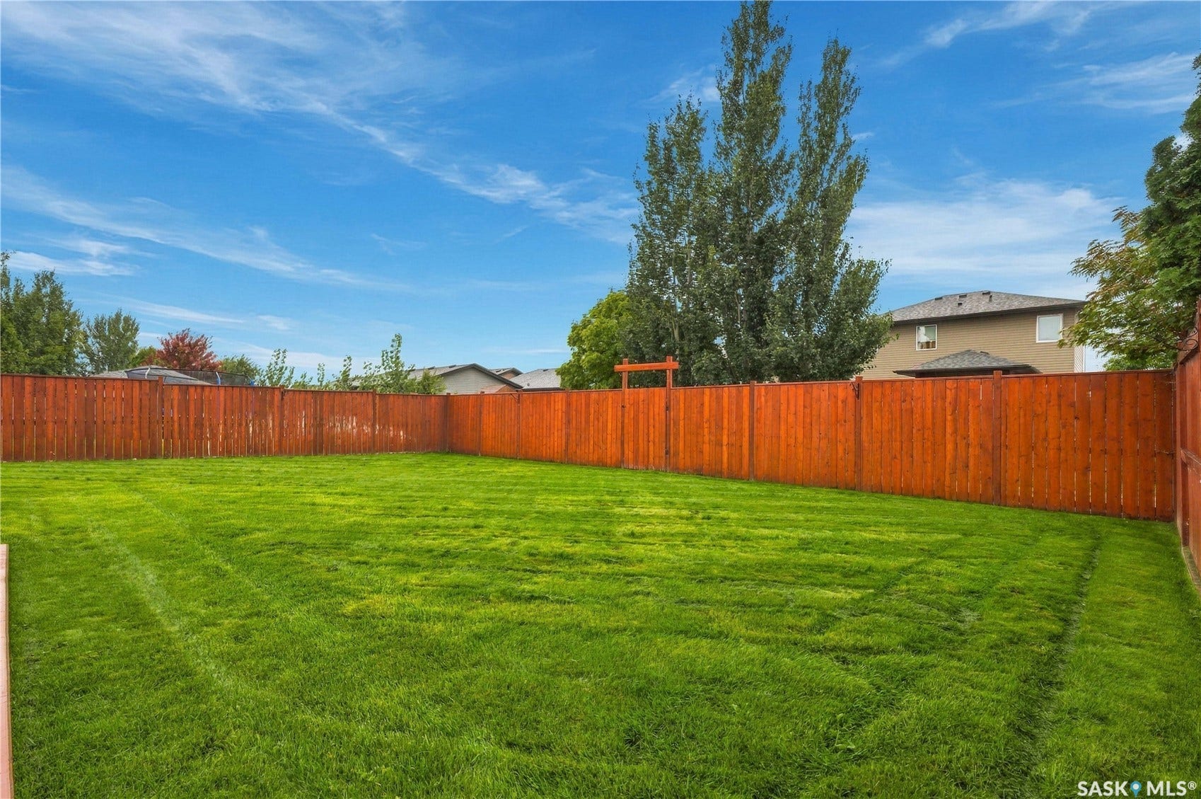 Expansive backyard featuring a manicured lawn and a privacy fence