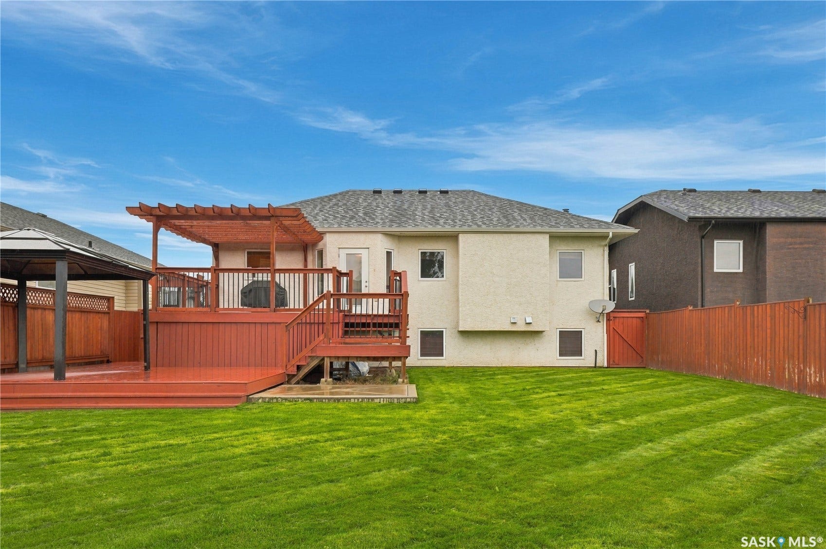 Expansive backyard featuring a manicured lawn, a multi-level wood deck with pergola, and a private gazebo
