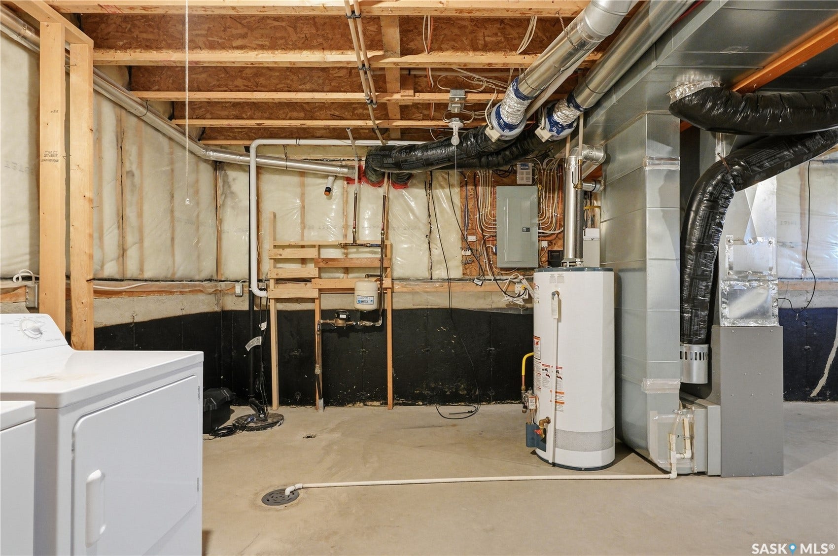 Unfinished basement with concrete flooring, exposed wood joists, utility sink, water heater, and HVAC system