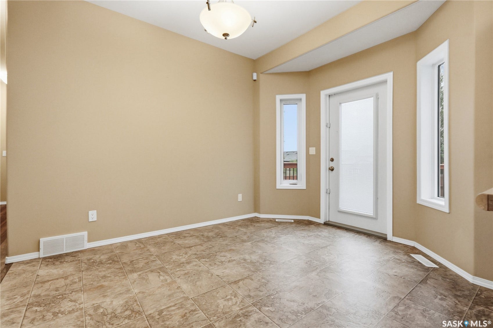 Tile flooring, multiple windows, a ceiling-mounted light fixture, and a frosted glass-paneled door