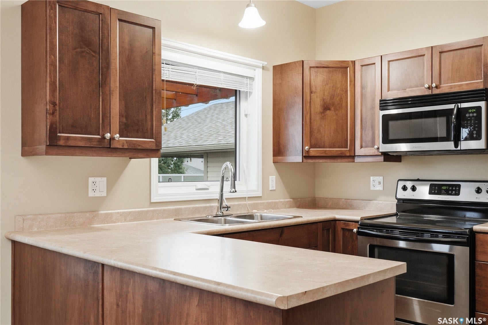 Kitchen with wood-finish cabinetry, stainless steel appliances, a double basin sink, and laminate countertops