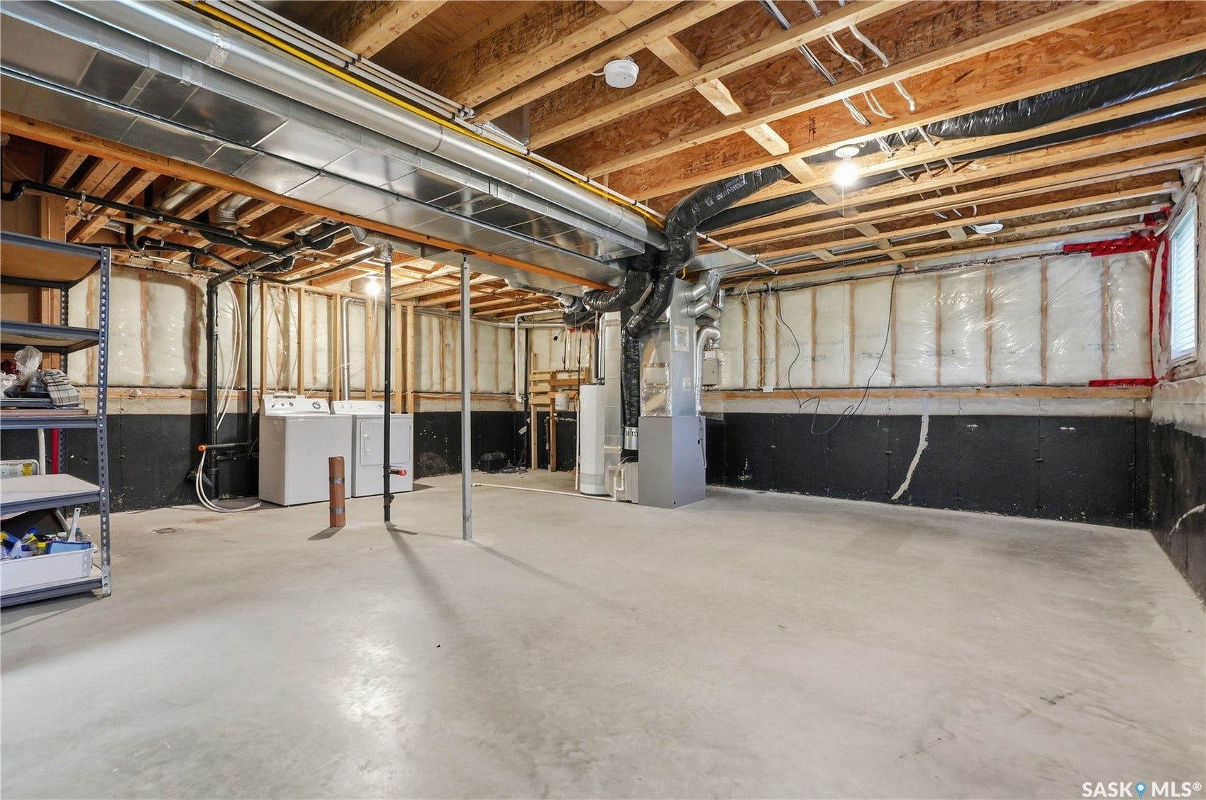 Unfinished basement with exposed ceiling joists, concrete flooring, and visible ductwork