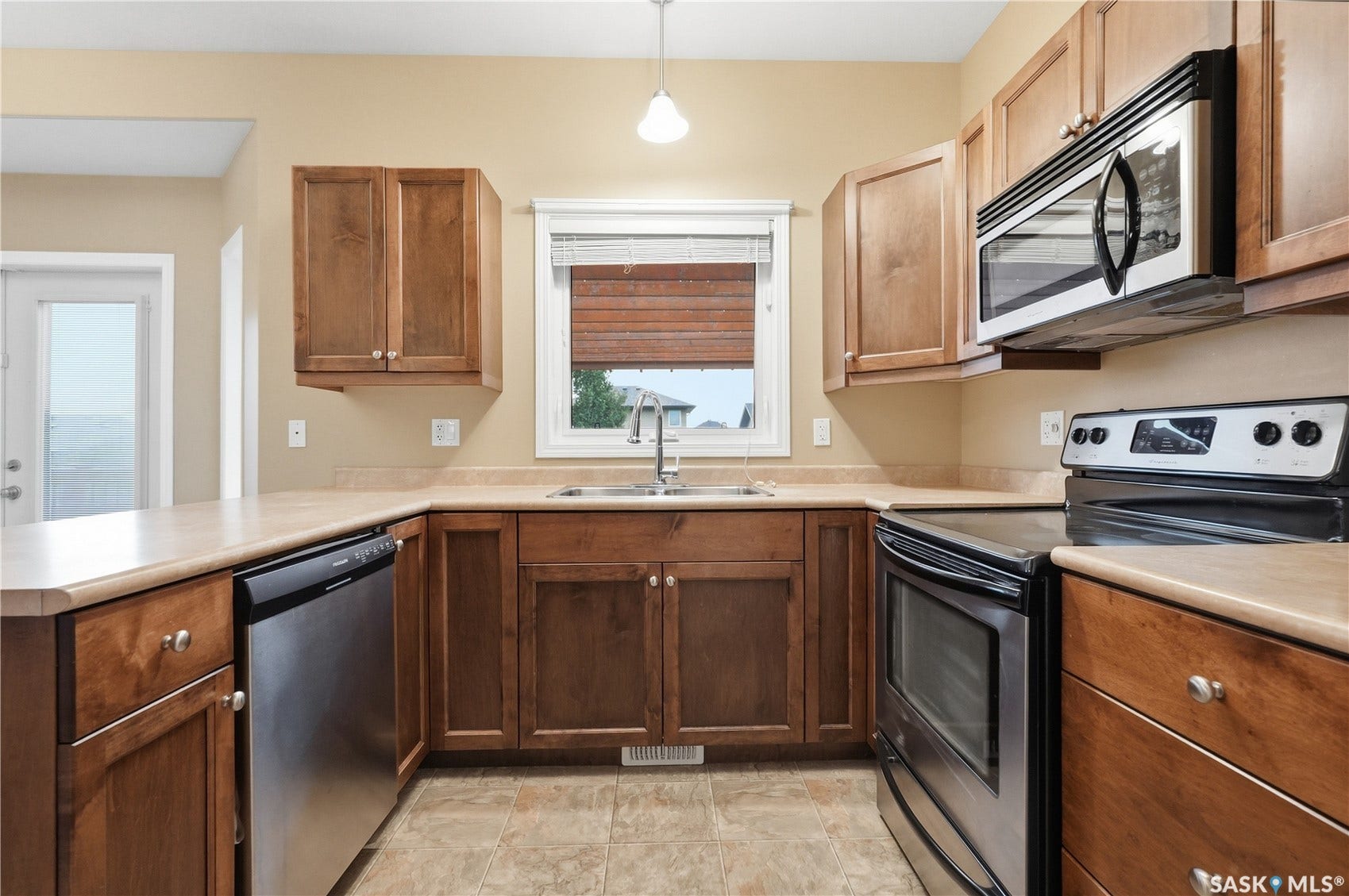 Kitchen featuring wood cabinetry, stainless steel appliances, a double basin sink, and laminate countertops