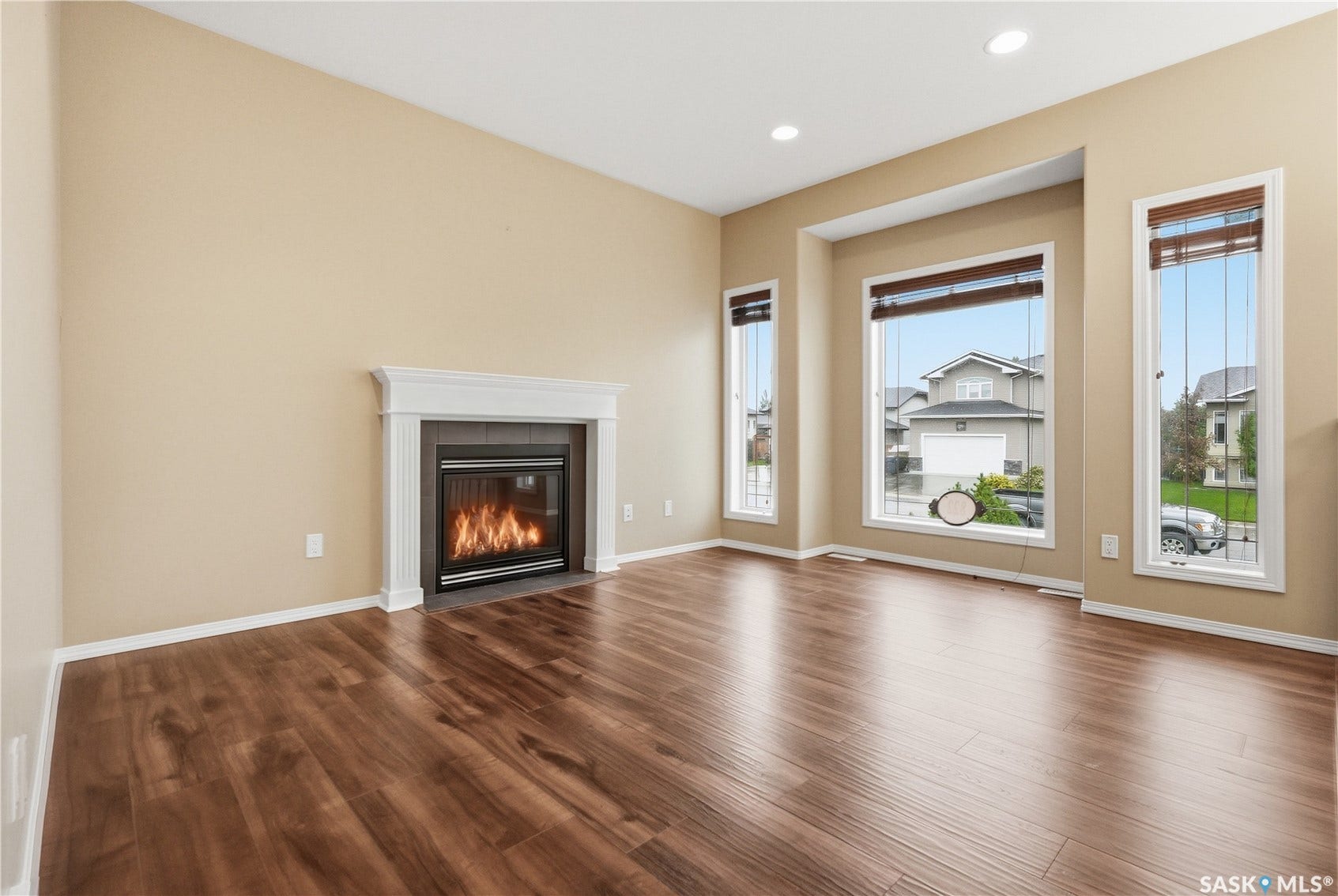 Wood-finish flooring, recessed lighting, and a fireplace with a white mantel