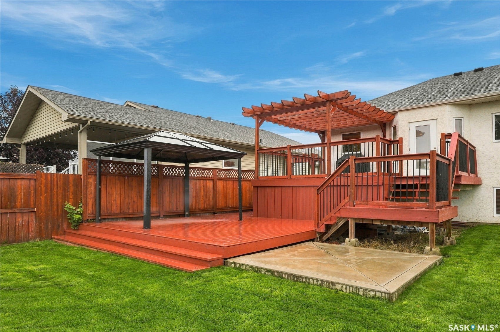 Expansive backyard with a manicured lawn, multi-level wood deck, and a wood pergola