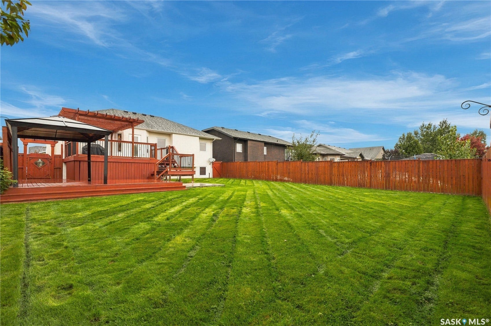 Expansive lawn area, multi-level wood deck, built-in pergola, privacy fencing, and a separate gazebo structure