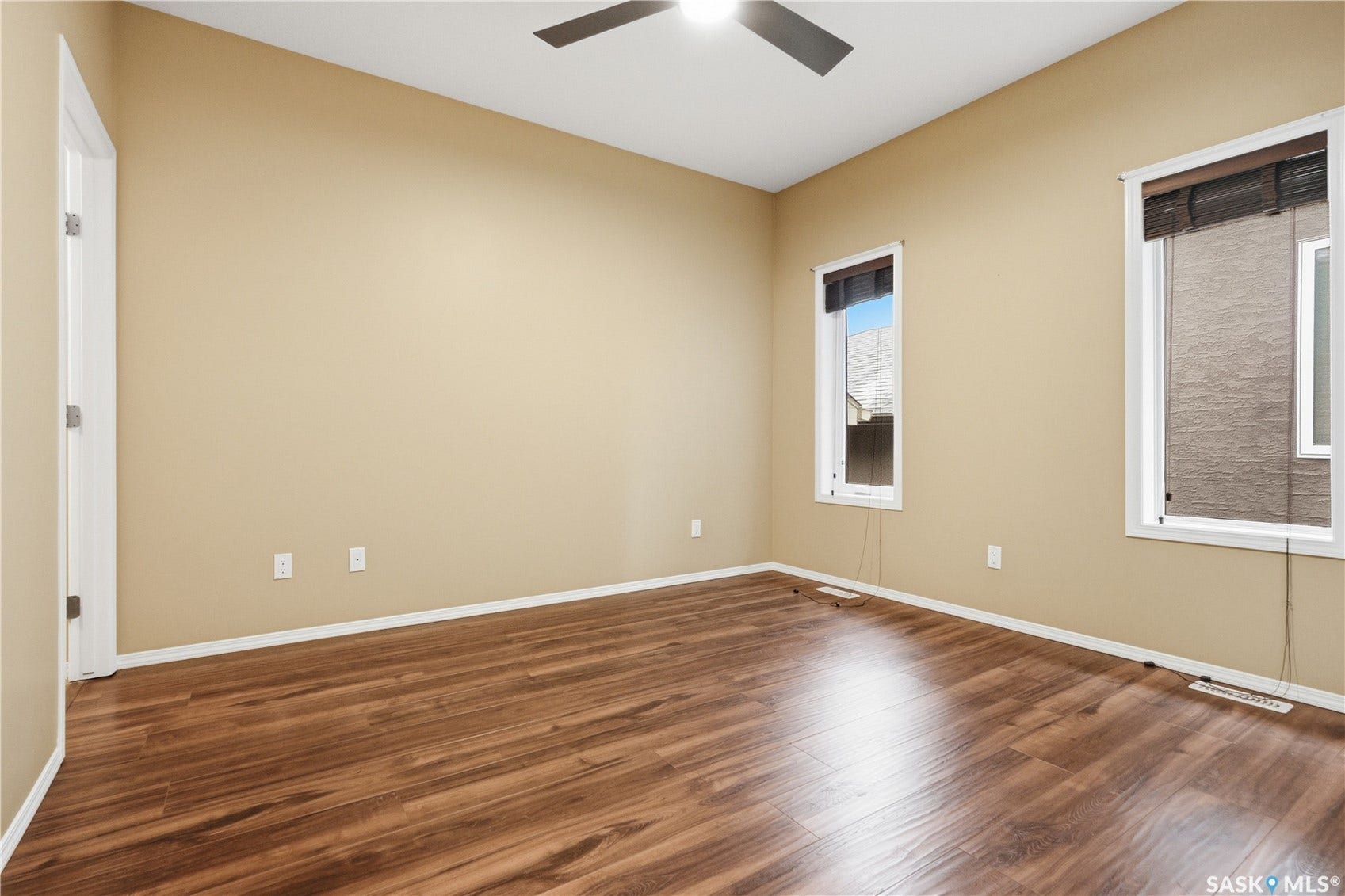 Wood-finish flooring, two windows with blinds, ceiling fan, and painted walls