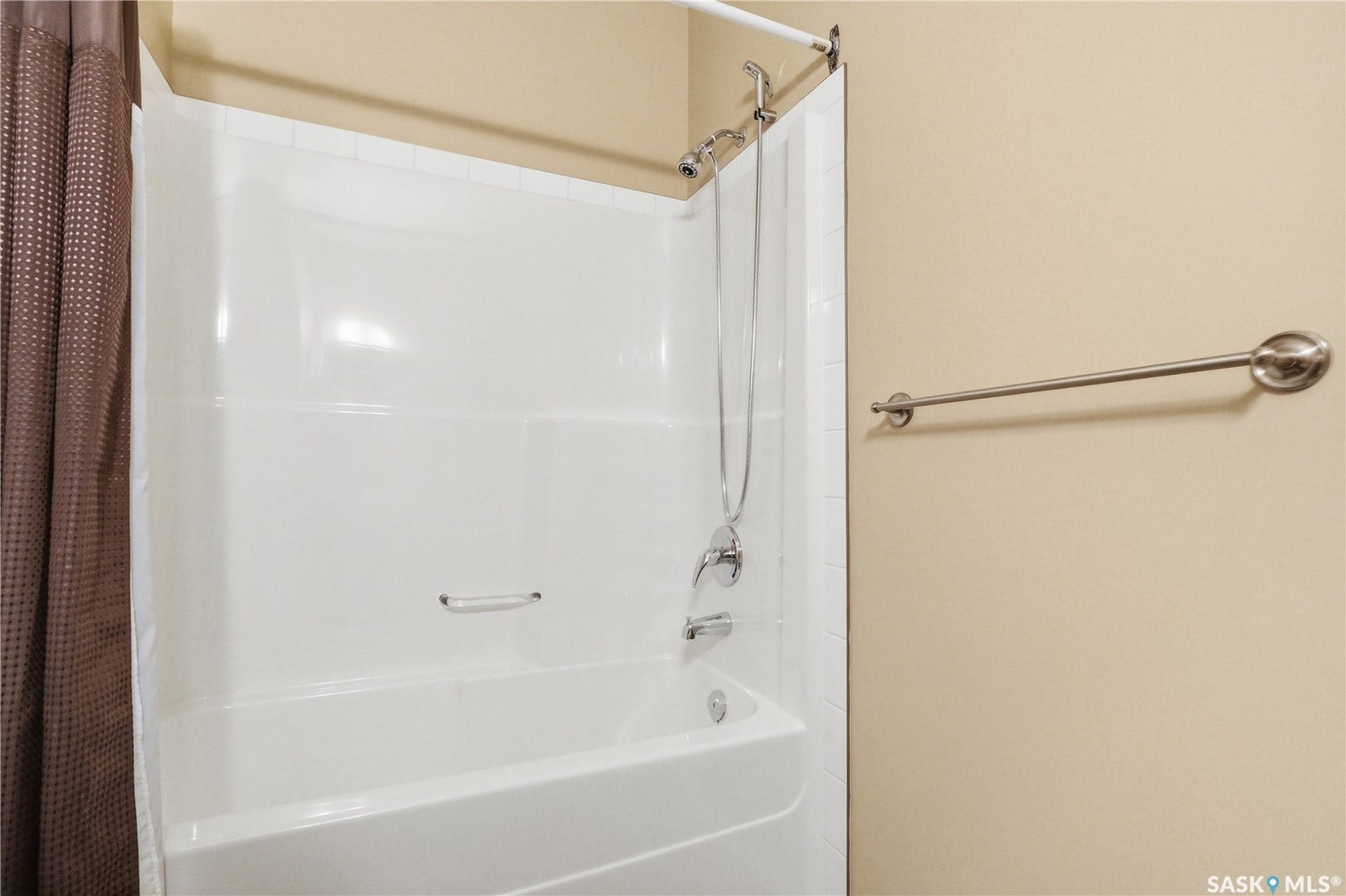 Bathtub and shower combination with a bright white surround and chrome fixtures