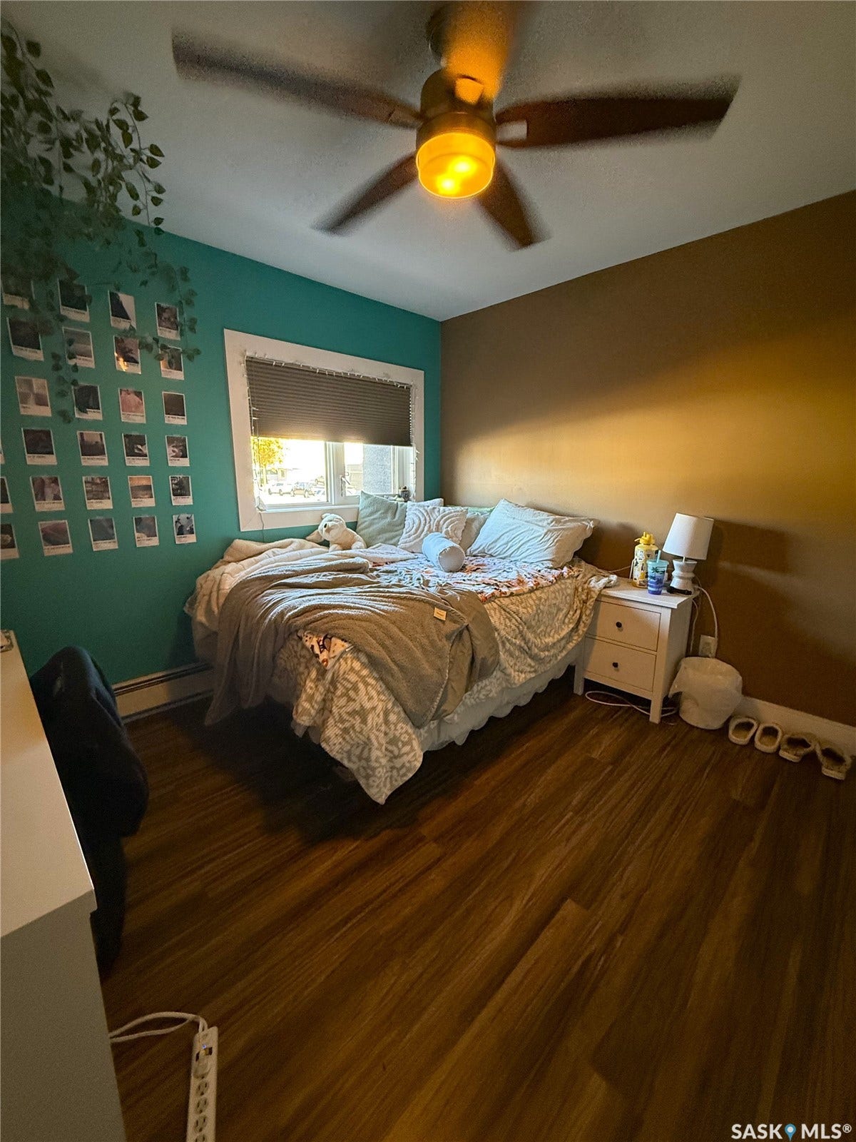 Wood-finish flooring with a ceiling fan light fixture and a window with blinds
