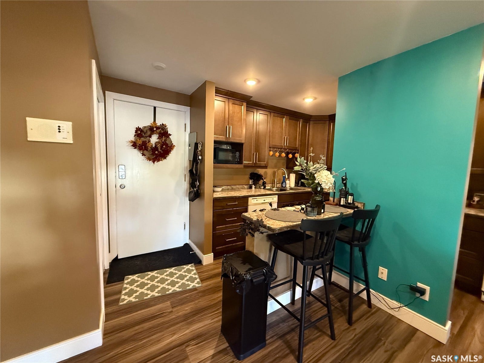 Galley kitchen featuring wood-finish cabinetry, stone-finish countertops, stainless steel sink, and built-in microwave