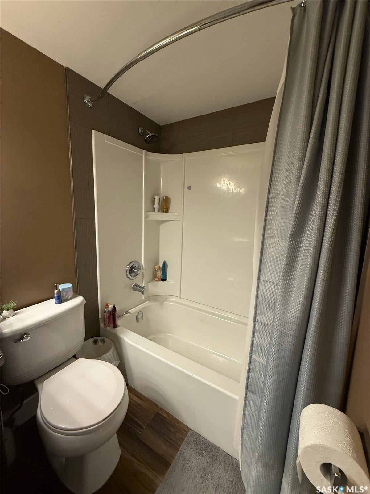 White bathtub and shower combination with a curved shower rod