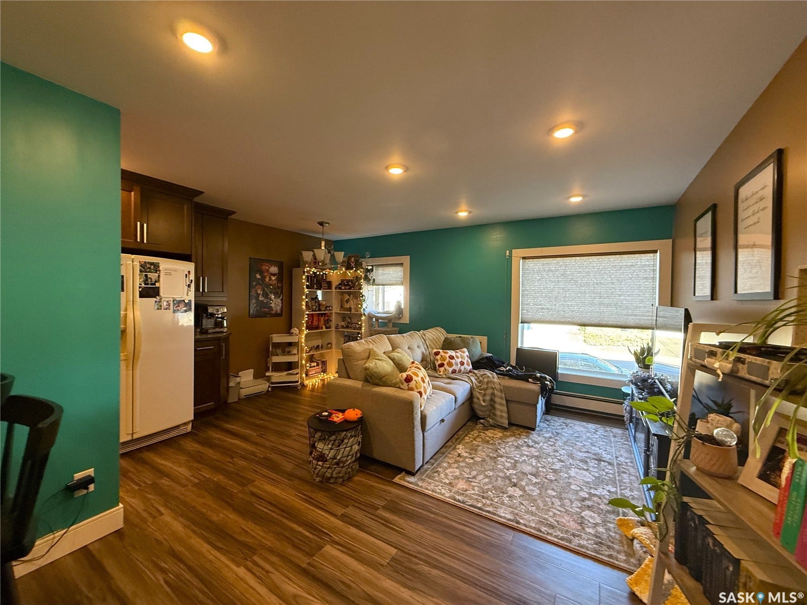 Recessed lighting, wood-finish flooring, dark wood cabinetry, white refrigerator, and window with blind