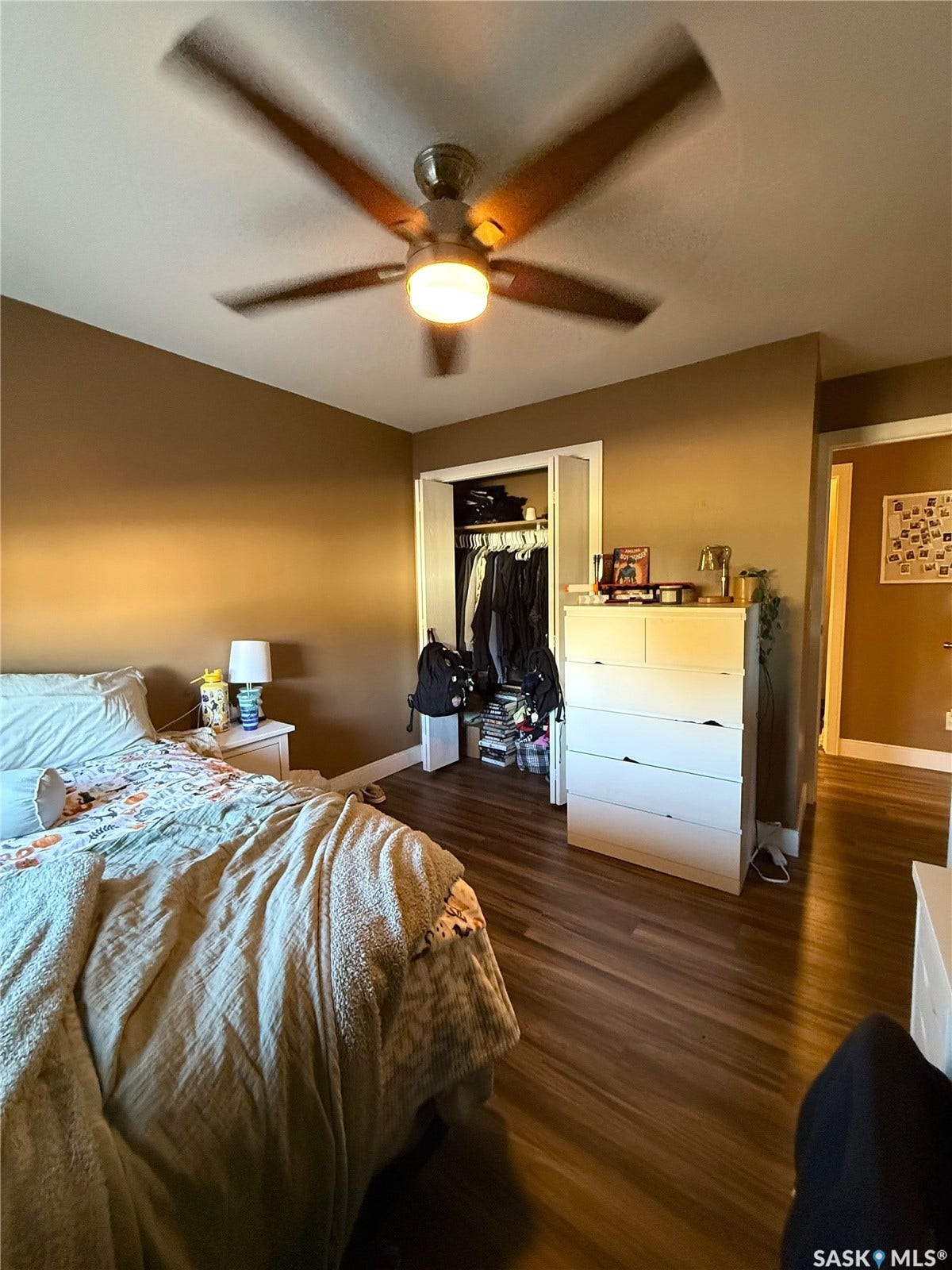 Wood-finish flooring, ceiling fan with integrated lighting, and an open closet space