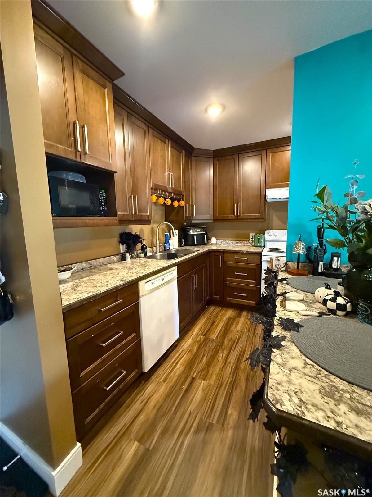 Kitchen featuring abundant wood-finish cabinetry, light-toned countertops, and wood-finish flooring