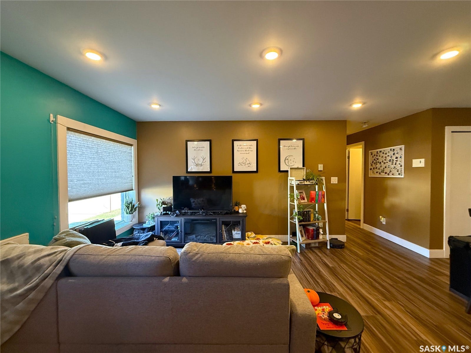 Recessed ceiling lighting, wood-finish flooring, and a large window with privacy blinds