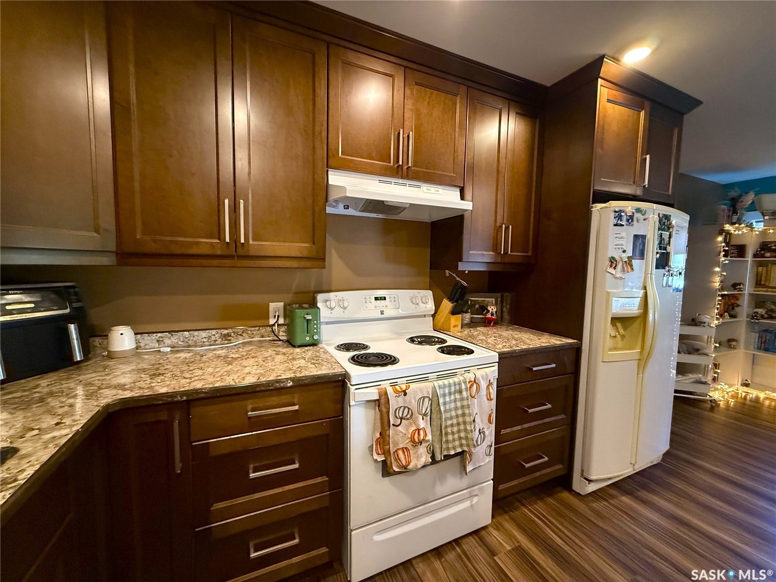 Wood-finish flooring, white range, wood cabinetry, and laminate countertops