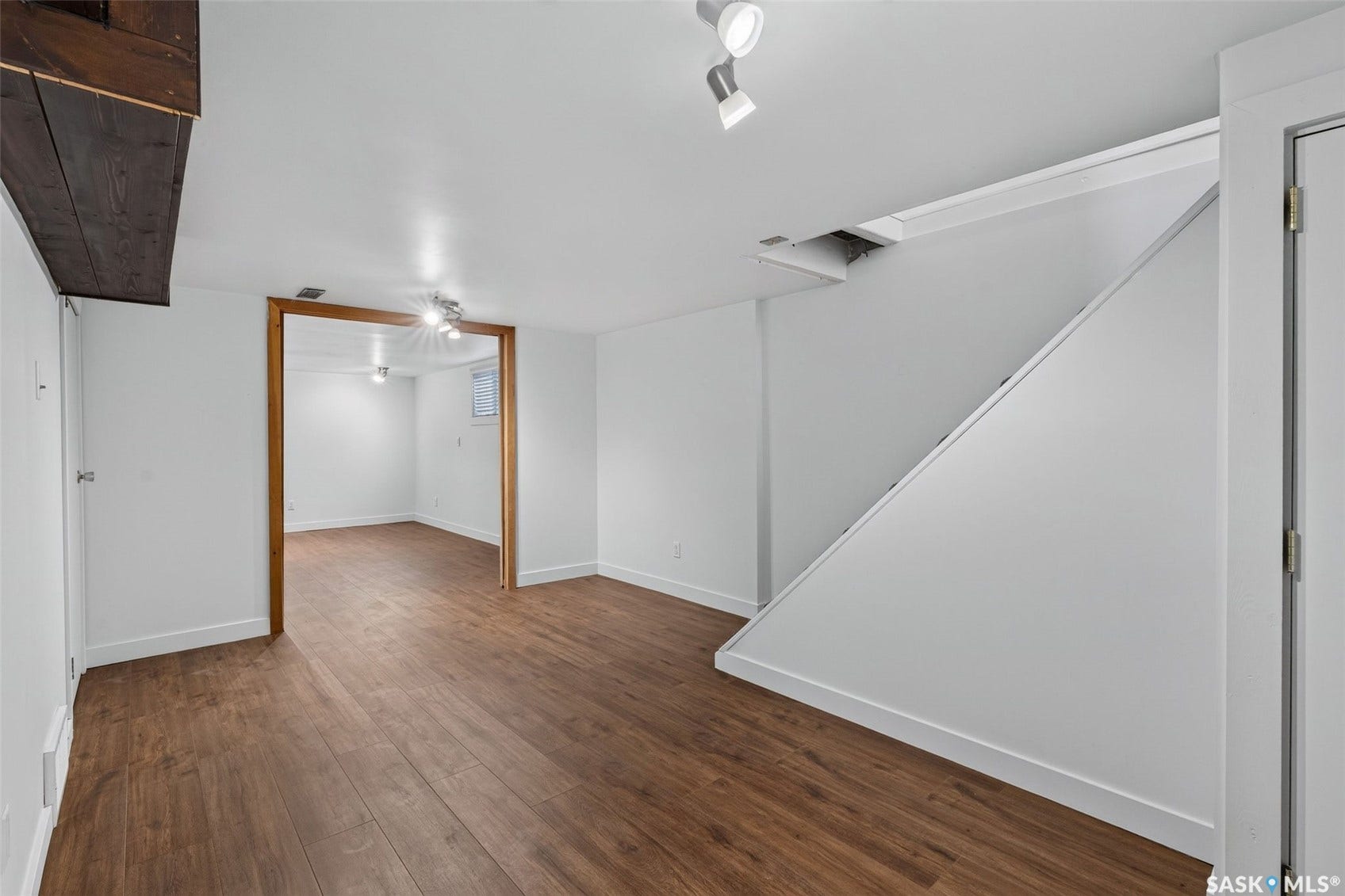Wood-finish flooring throughout, white walls, recessed lighting, and a wood-trimmed doorway