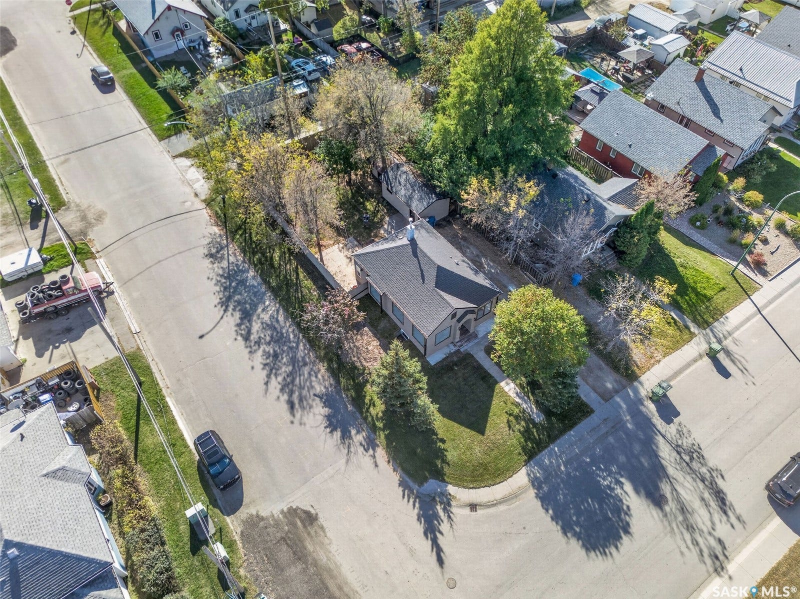 Corner lot property featuring a dark-toned roof, established trees, and surrounding neighborhood homes