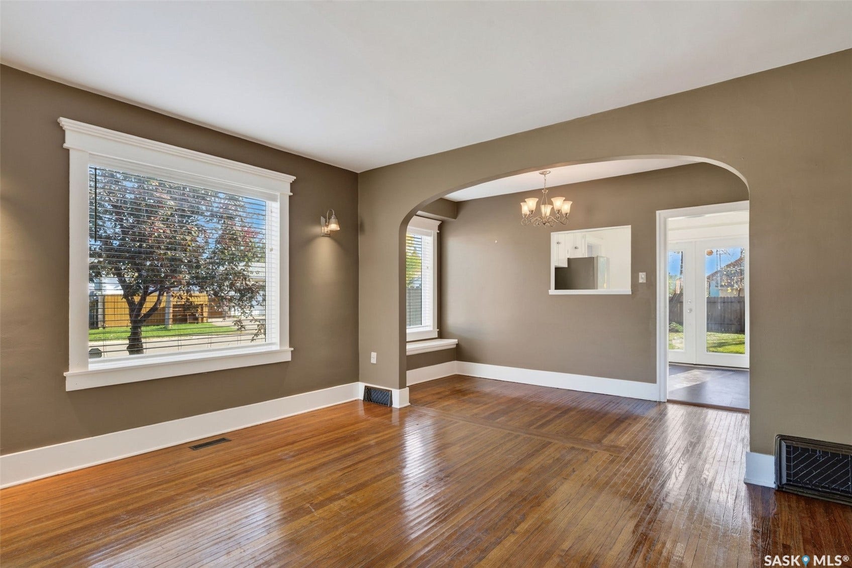 Wood-finish flooring, white trim, arched doorway, and built-in wall sconces